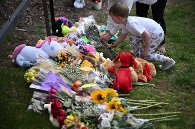 A boy leaves flowers at a makeshift memorial for victims by the Covenant School building at the Covenant Presbyterian Church following a shooting, in Nashville, Tennessee, March 28, 2023. A heavily armed former student killed three young children and three staff in what appeared to be a carefully planned attack at a private elementary school in Nashville on Monday, before being shot dead by police. Chief of Police John Drake named the suspect as Audrey Hale, 28, who the officer later said identified as transgender. 
