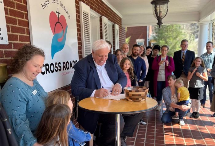 West Virginia Gov. Jim Justice signs House Bill 2002 into law at Cross Roads Pregnancy Care Center in Charleston, W.Va., as clinic staff and pro-life activists look on, March 29, 2023. 