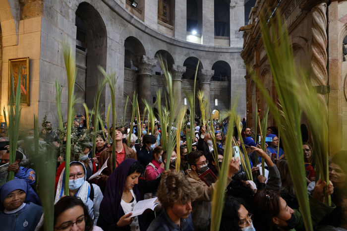 Worshipers carry palm branches as they circle the aedicule during the Palm Sunday procession at the Church of the Holy Sepulchre in Jerusalem's Old City, on April 10, 2022