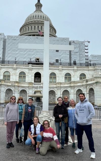 Participants in a Good Friday service at the United States Capitol, spearheaded by the Christian Defense Coalition, pose in front of a 15-foot cross, April 7, 2023.