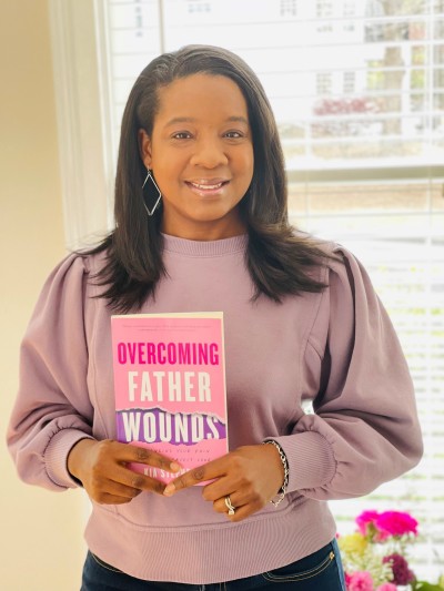 Author Kia Stephens poses with her self-help Christian book 'Overcoming Father Wounds: Exchanging Your Pain For God’s Perfect Love.' .