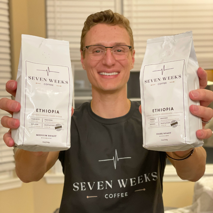 Seven Weeks Coffee Founder Anton Krecic holds up packages of coffee. 