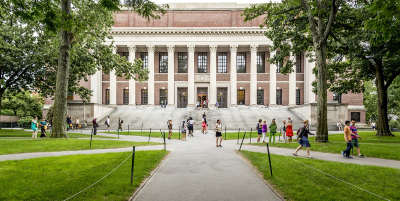 View of the iconic architecture of the Harvard University in Cambridge, Mass., with some locals, tourists and students passing by.