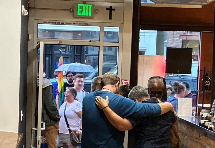 A group gathers in prayer inside the Christian-owned Drip Cafe in Denver as communist and LGBT protesters rally just outside in June 2023.