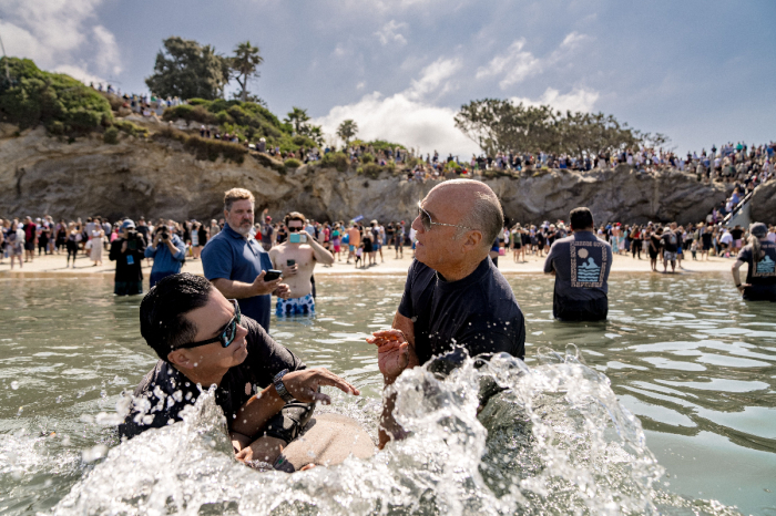 Greg Laurie helps baptize an attendee of a mass baptism held at Pirate's Cove Beach in California on July 8, 2023. 