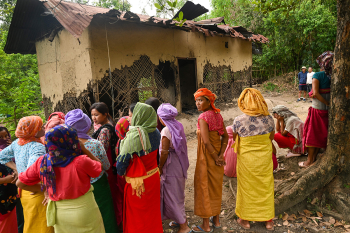 In this photo taken on July 22, 2023, a group of Meira Paibi women of the Meiti community gather in front of the partially charred house of an alleged suspect of a viral sexual assault video in Pechi Awang Leikai village of the Thoubal district of north eastern state of Manipur. A clip went viral on July 19, 2023, showing two women reported to be from the Kuki tribal group walking naked along a street while being jeered at and harassed by a mob reportedly from the Meitei community. 