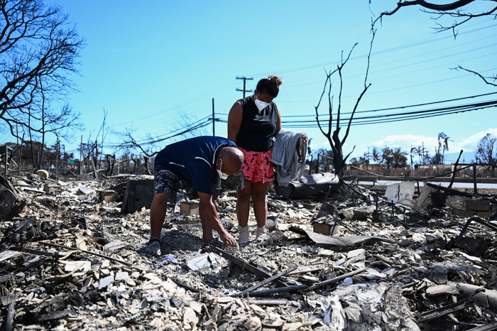 Davilynn Severson and Hano Ganer look for belongings through the ashes of their family's home in the aftermath of a wildfire in Lahaina, western Maui, Hawaii on August 11, 2023. A wildfire that left Lahaina in charred ruins has killed at least 93 people, authorities said on August 11, making it one of the deadliest disasters in the US state's history. Brushfires on Maui, fueled by high winds from Hurricane Dora passing to the south of Hawaii, broke out August 8 and rapidly engulfed Lahaina. 