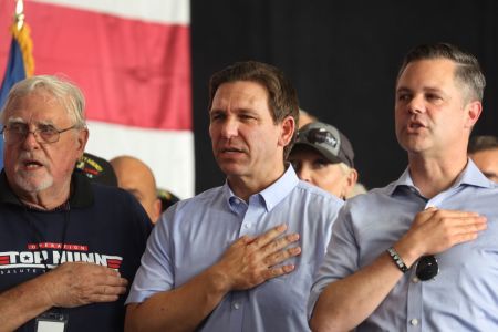 Republican presidential candidate Florida Governor Ron DeSantis (C) and U.S. Rep. Zach Nunn (R) listen to the National Anthem at Nunn's 'Operation Top Nunn: Salute to Our Troops' fundraiser on July 15, 2023 in Ankeny, Iowa. The day before, DeSantis joined several other Republican presidential candidates at the Family Leadership Summit in nearby Des Moines.