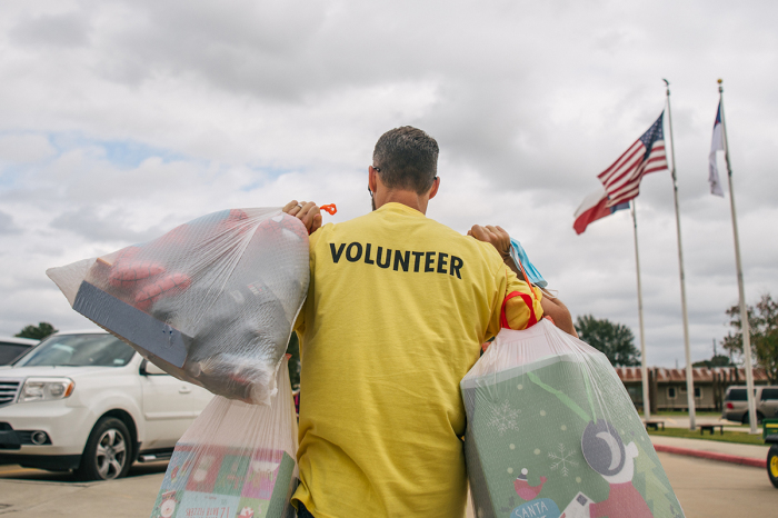 A community volunteer helps a family carry gifts out during the Families Feeding Families event at the Salem Community Center on November 24, 2021, in Houston, Texas. 