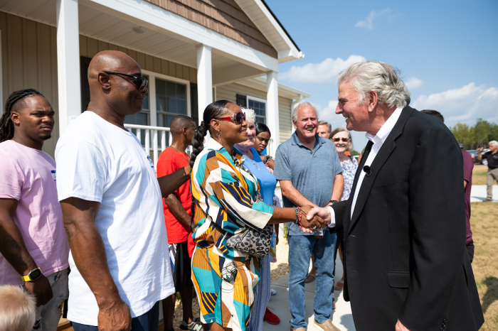 Latasha Hayes stands in front of her new home with her family and shakes hands with the Rev. Franklin Graham, president and CEO of Samaritan's Purse, in September 2023. 
