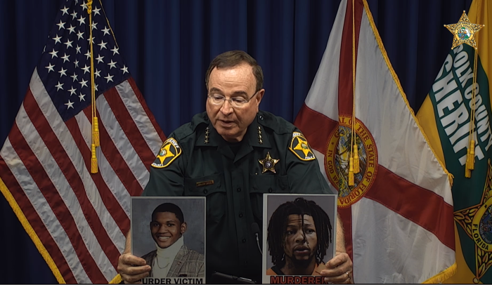 Polk County Sheriff Grady Judd holds up photos of murder victim, 20-year-old Roderick Wilson Jr. (L) and murder suspect, 22-year-old Taquion 'Quan' Cotton (R), at a press conference in Florida on October 23, 2023.