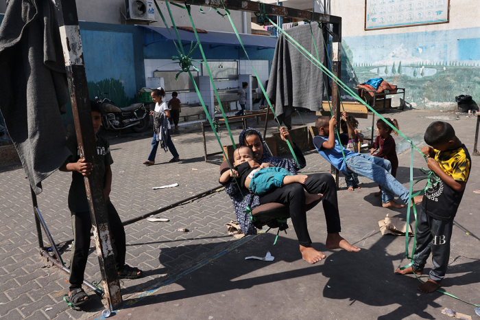 Children play on a swing in the playground of a school run by the United Nations Relief and Works Agency for Palestine Refugees (UNRWA), that has been converted into a shelter for displaced Palestinians in Rafah in the southern Gaza Strip on October 25, 2023, amid ongoing battles between Israel and the Palestinian group Hamas. 