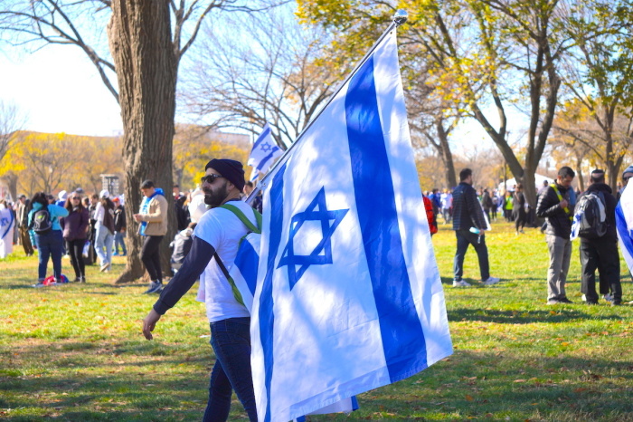 A demonstrator at the Americans March for Israel carries an Israeli flag alongside other demonstrators in support of the effort to combat antisemitism and show support for Israel's war against Hamas in Washington, D.C., on November 14, 2023.