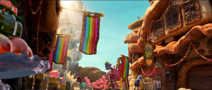 A screenshot of a trailer for 'Trolls Band Together' shows a number of rainbow-themed flags hanging as part of a royal wedding.
