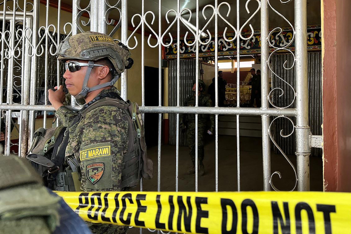 Military personnel stand guard at the entrance of a gymnasium while police investigators look for evidence after a bomb attack at Mindanao State University in Marawi, Lanao del sur province on December 3, 2023. At least three people were killed and seven wounded in a bomb attack on a Catholic mass in the insurgency-plagued southern Philippines on December 3, officials said. 