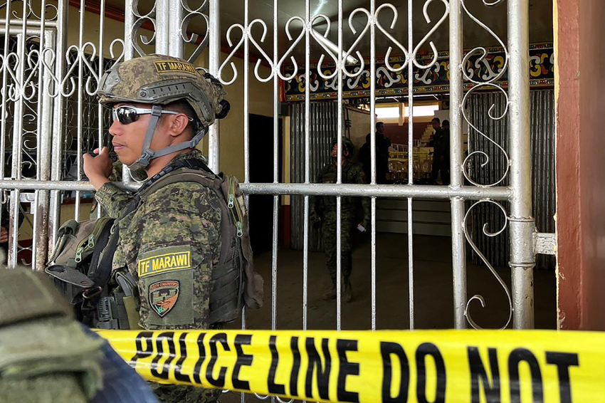 Military personnel stand guard at the entrance of a gymnasium while police investigators look for evidence after a bomb attack at Mindanao State University in Marawi, Lanao del sur province on December 3, 2023. At least three people were killed and seven wounded in a bomb attack on a Catholic mass in the insurgency-plagued southern Philippines on December 3, officials said.