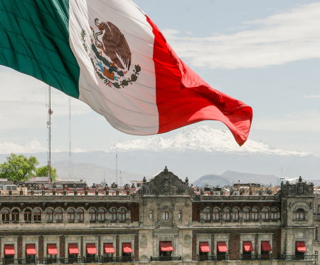 The national flag of Mexico hoisted above the National Palace government offices in the Zocalo de la Mexico City, Mexico.