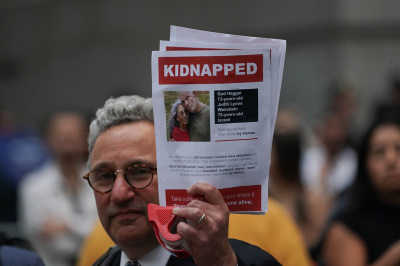 A supporter of Israel holds a picture of kidnapped Israeli hostages Gad Haggai and Judith Lynne Weinstein during the 'Flood Wall Street for Gaza' rally outside the New York Stock Exchange on October 26, 2023, in New York. Over 1,200 civilians were murdered and 240 others were taken hostage by Hamas terrorists based in the Gaza Strip after they invaded southern Israel in an unprecedented attack triggering a war declared by Israel on Hamas with retaliatory bombings on Gaza. 