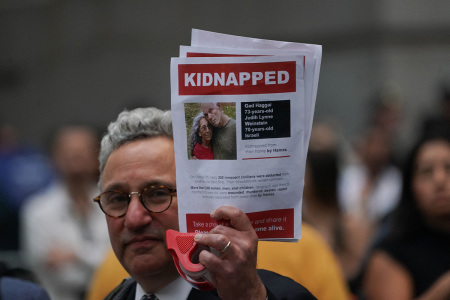 A supporter of Israel holds a picture of kidnapped Israeli hostages Gad Haggai and Judith Lynne Weinstein during the 'Flood Wall Street for Gaza' rally outside the New York Stock Exchange on October 26, 2023, in New York. Over 1,200 civilians were murdered and 240 others were taken hostage by Hamas terrorists based in the Gaza Strip after they invaded southern Israel in an unprecedented attack triggering a war declared by Israel on Hamas with retaliatory bombings on Gaza.