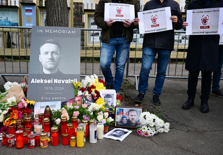 People stand next to a makeshift memorial of flowers and candles for Kremlin critic Alexei Navalny at the Russian embassy in Bucharest, Romania, on February 18, 2024. Alexei Navalny's supporters accused Russian authorities of being