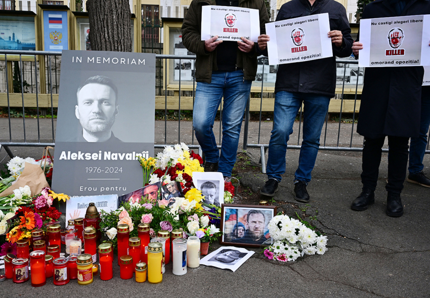 People stand next to a makeshift memorial of flowers and candles for Kremlin critic Alexei Navalny at the Russian embassy in Bucharest, Romania, on February 18, 2024. Alexei Navalny's supporters accused Russian authorities of being