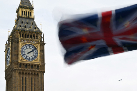 A photograph taken on January 31, 2024, shows a Union Jack flag with behind a a European Union flag flapping in the air in front of the Elizabeth Tower, commonly known by the name of the clock's bell 'Big Ben,' at the Palace of Westminster, home to the Houses of Parliament, central London.