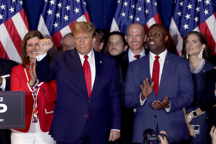 Republican presidential candidate and former President Donald Trump gestures to supporters as Sen. Tim Scott, R-S.C., looks on after Trump spoke during an election night watch party at the State Fairgrounds on February 24, 2024, in Columbia, South Carolina. Trump defeated opponent Nikki Haley in the South Carolina Republican primary. 