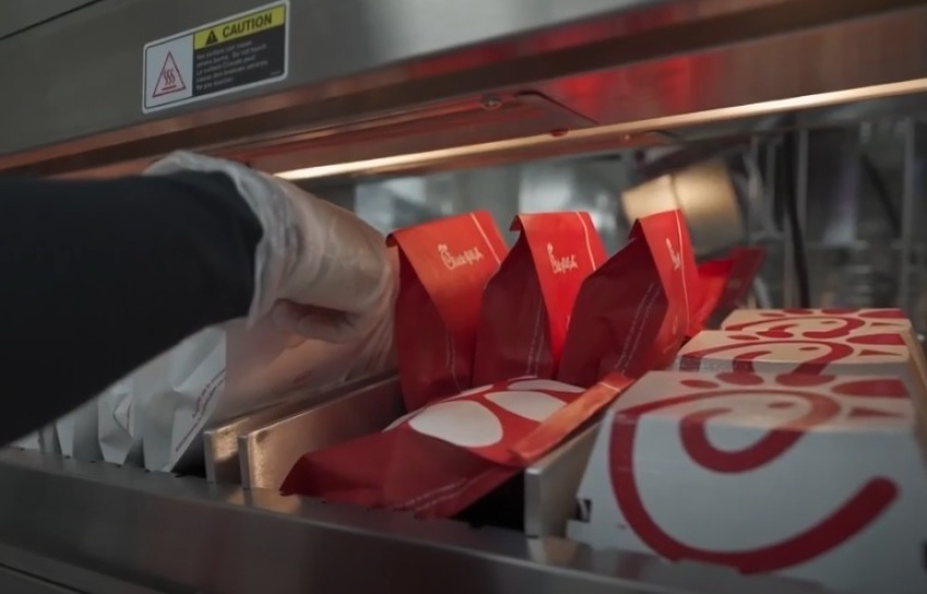 A Chick-fil-A employee places sandwiches on a heated rack in New York City.