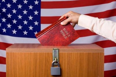 Human hand inserting Bible to ballot box before American flag. The ballot box is locked.