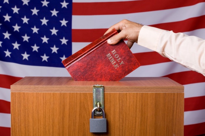 Human hand inserting bible to ballot box before American Flag, The ballot box is locked.