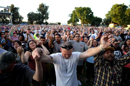 Attendees hold hands and pray as the Rev. Franklin Graham speaks during Franklin Graham's 'Decision America' California tour at the Stanislaus County Fairgrounds on May 29, 2018, in Turlock, California. Graham is touring California for the weeks leading up to the California primary election on June 5 with a message for Evangelicals to vote.