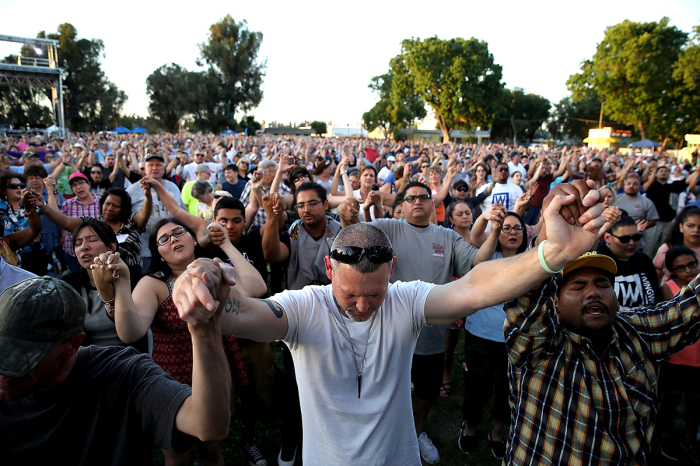 Attendees hold hands and pray as the Rev. Franklin Graham speaks during Franklin Graham's 'Decision America' California tour at the Stanislaus County Fairgrounds on May 29, 2018, in Turlock, California. Graham is touring California for the weeks leading up to the California primary election on June 5 with a message for Evangelicals to vote. 