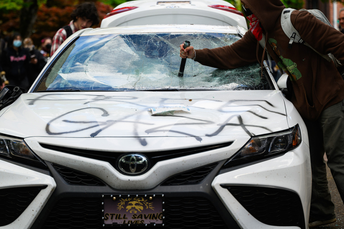 Protesters deface a car after a counter-protester drove toward the crowd gathered at the Portland State University campus, exited their vehicle and deployed mace on May 2, 2024, in Portland, Oregon. Pro-Palestinian encampments have sprung up at college campuses around the country with some protestors calling for schools to divest from Israeli interests amid the ongoing war in Gaza. 