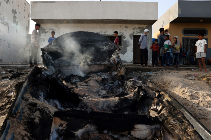 Palestinians stand around a charred fishing boat that was hit by an Israeli airsrike on the Mediterranean coast of Rafah in the southern Gaza Strip on May 22, 2024, amid the ongoing conflict between Israel and the Palestinian Hamas group. 