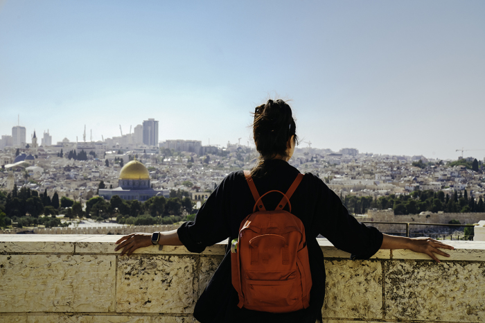 Woman standing at The Old Town with the Dome of the Rock at the sunset from Mount of Olives