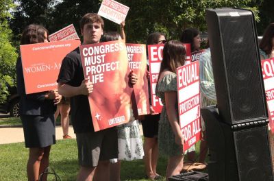Pro-life advocates hold signs during Live Action's press conference in Washington, D.C., on June 12, 2024, as pro-choice protestors stand behind the pro-life advocates.