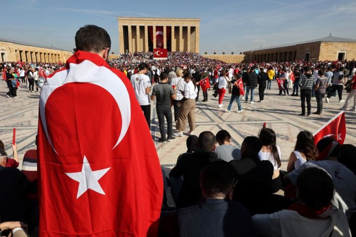 A man wrapped in Turkey's national flag in front of Anitkabir, the mausoleum of Turkish Republic founder Mustafa Kemal Ataturk, as people gather to mark the 100th anniversary of the Republic of Turkey in Ankara, October 29, 2023. 