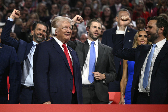 Former U.S. President and 2024 Republican presidential candidate Donald Trump (bottom left) smiles as he is cheered on by U.S. Senator from Ohio and 2024 Republican vice presidential candidate J.D. Vance (right) and his sons Donald Trump Jr. and Eric Trump on the first day of the 2024 Republican National Convention at the Fiserv Forum in Milwaukee, Wisconsin, July 15, 2024. Donald Trump won the formal nomination as the Republican presidential candidate and chose J.D. Vance, a right-wing loyalist, as his running mate, kicking off a triumphalist party convention following last weekend's failed assassination attempt. 