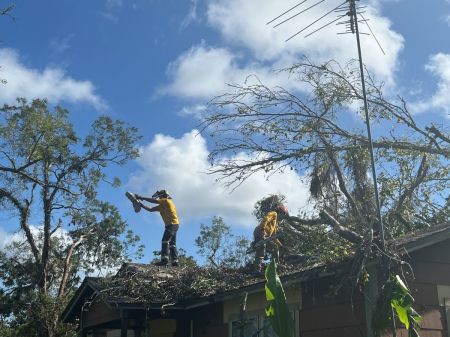 Volunteers with Texans on Mission assist a homeowner clear debris off a roof in the aftermath of Hurricane Beryl in Freeport, Texas, in July 2024.