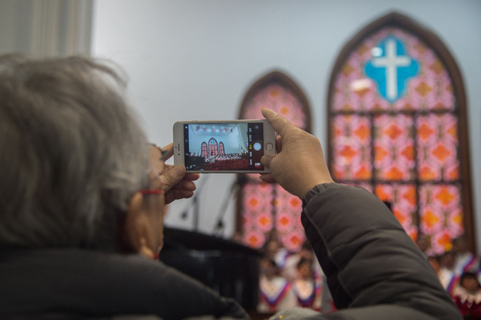 A churchgoer takes photos of the clergy after Christmas Day mass at a Protestant church in downtown Shanghai on December 25, 2021. 