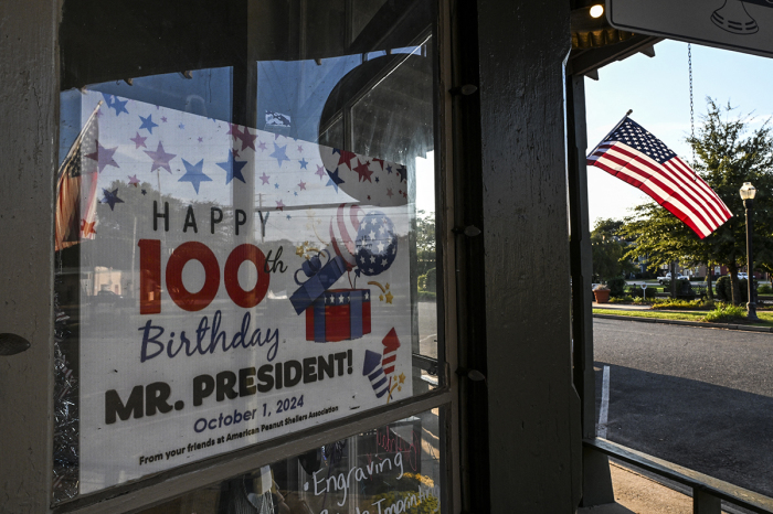 A placard celebrating former U.S. President Jimmy Carter's 100th Birthday is displayed in the window of a shop in Plains, Georgia, on Sept. 30, 2024. The military flyover is ready, the songs have been rehearsed: Plains, Georgia is waiting to celebrate Jimmy Carter's 100th birthday on Oct. 1, when its hometown hero becomes the only ever U.S. president to reach the centennial mark. Carter's longevity -- he announced he was going into hospice care more than 19 months ago -- has defied all expectations. 