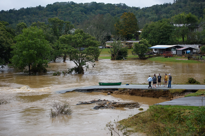 Friends talk after having canoed the flooded South Fork New River for 32 minutes and landing at a washed out road on Sept. 27, 2024, in Boone, North Carolina. 'We saw trailers floating by, and cars toppled over,' said one of the friends. Rains from what was Hurricane Helene have dropped more than a foot of rain across much of the region. 