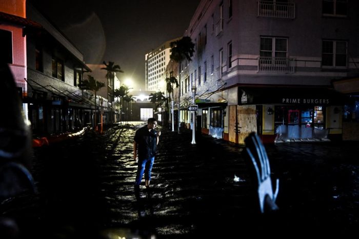 A man talks on his phone as he walks through water-flooded streets after Hurricane Milton made landfall in Fort Myers, Florida, on October 9, 2024. 