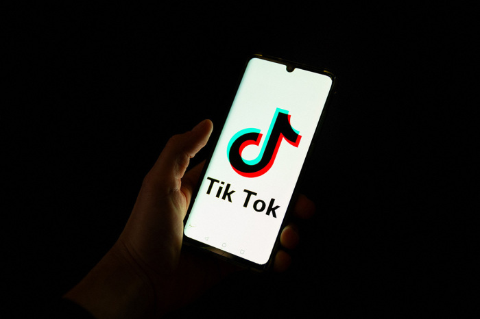 This photograph taken on April 19, 2024, shows a man holding a smartphone displaying the logo of Chinese social media platform TikTok in an office in Paris 