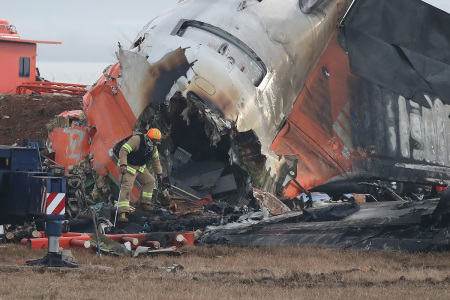 Firefighters work at the wreckage of a passenger plane at Muan International Airport on Dec. 30, 2024, in Muan-gun, South Korea. A plane carrying 181 people, Jeju Air Flight 7C2216, crashed at Muan International Airport in South Korea after skidding off the runway and colliding with a wall, resulting in an explosion. Early reports said that at least 179 people had died. 