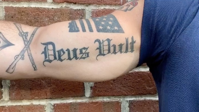 A photo of Pete Hegseth's bicep tattooed with the Latin phrase