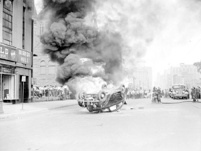 Firefighters attempt to extinguish a car set on fire on Woodward Avenue at Charlotte Street during the 1943 Race Riot in Detroit, Michigan.