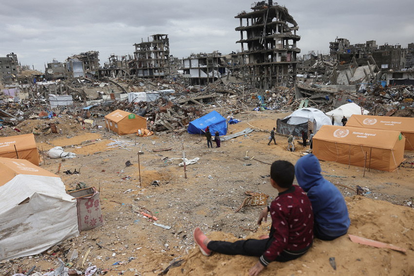 Displaced Palestinian children sit on a sand mound overlooking tents set up amid destroyed buildings in Jabalia in the northern Gaza Strip on Feb. 6, 2025, during a truce in the war between Israel and Hamas.