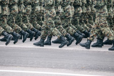 Soldiers dressed in army camouflage march in formation. 