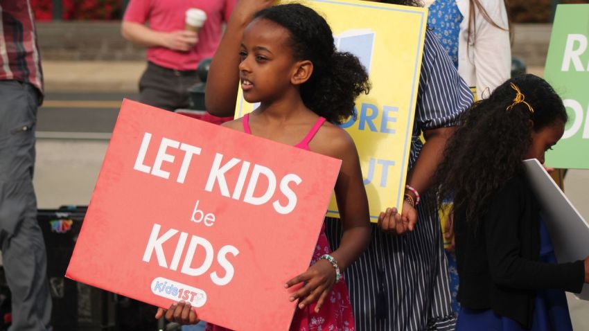 A little girl holding a "Let Kids be Kids" sign stands outside of the U.S. Supreme Court on April 22, 2025. The girl attended a rally in front of the court as it prepared to hear oral arguments for the case "Mahmoud v. Taylor."